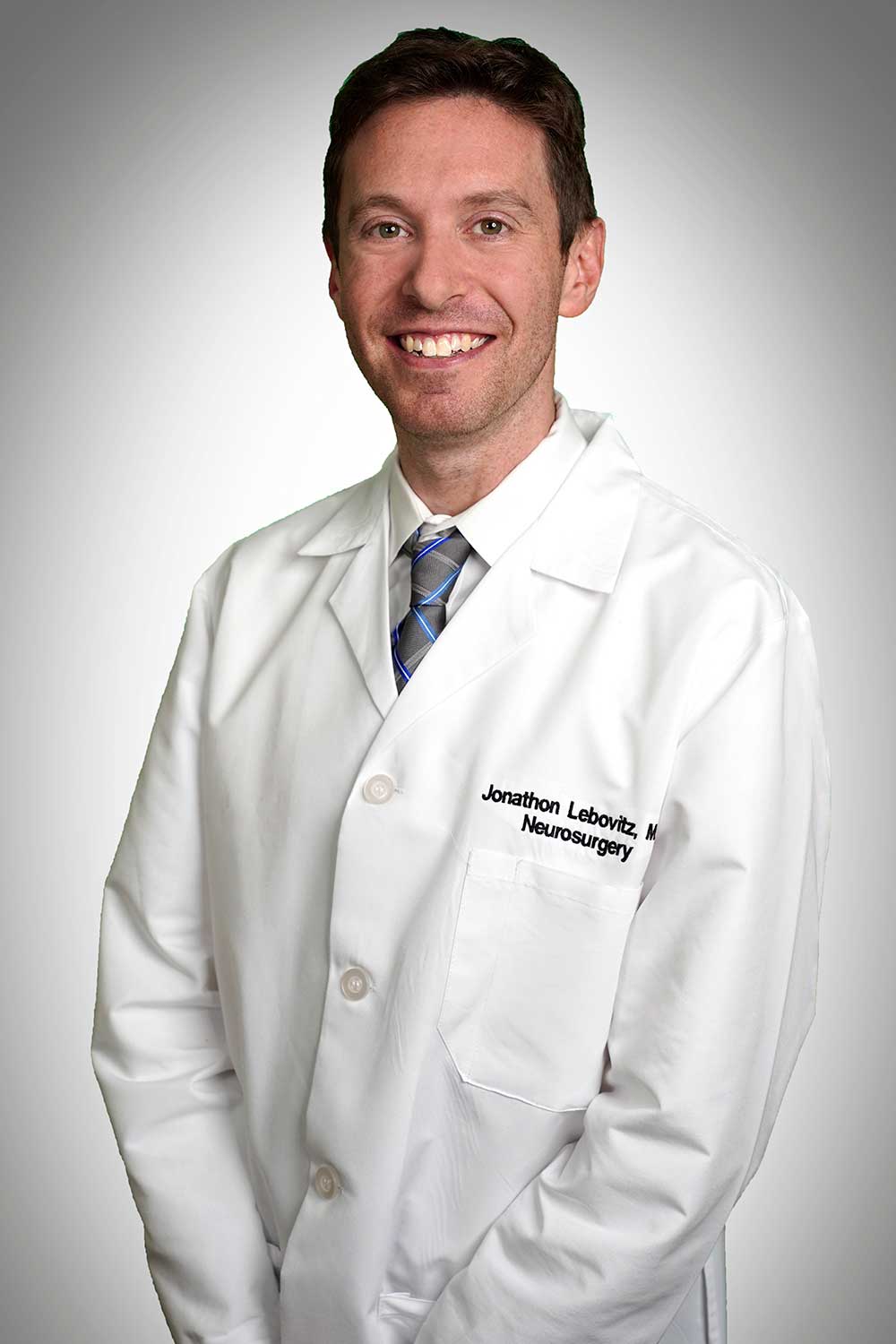 Headshot of neurosurgeon Jonathan Lebovitz wearing his lab coat and smiling.