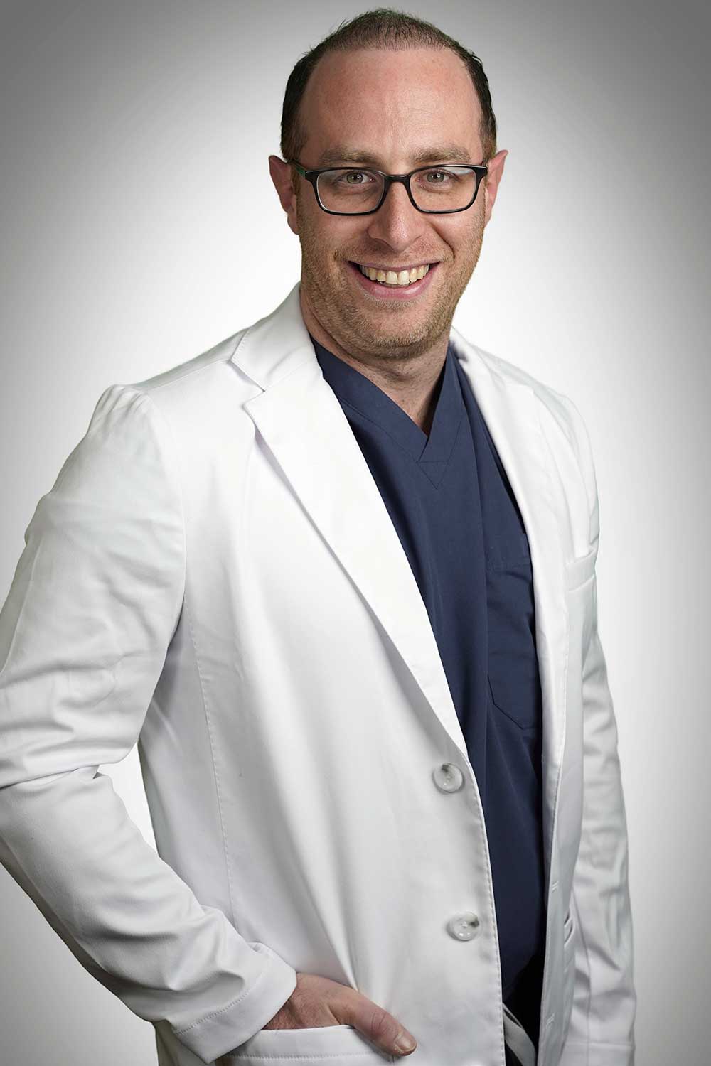 Headshot of neurosurgeon Joshua Marcus wearing his lab coat and smiling.
