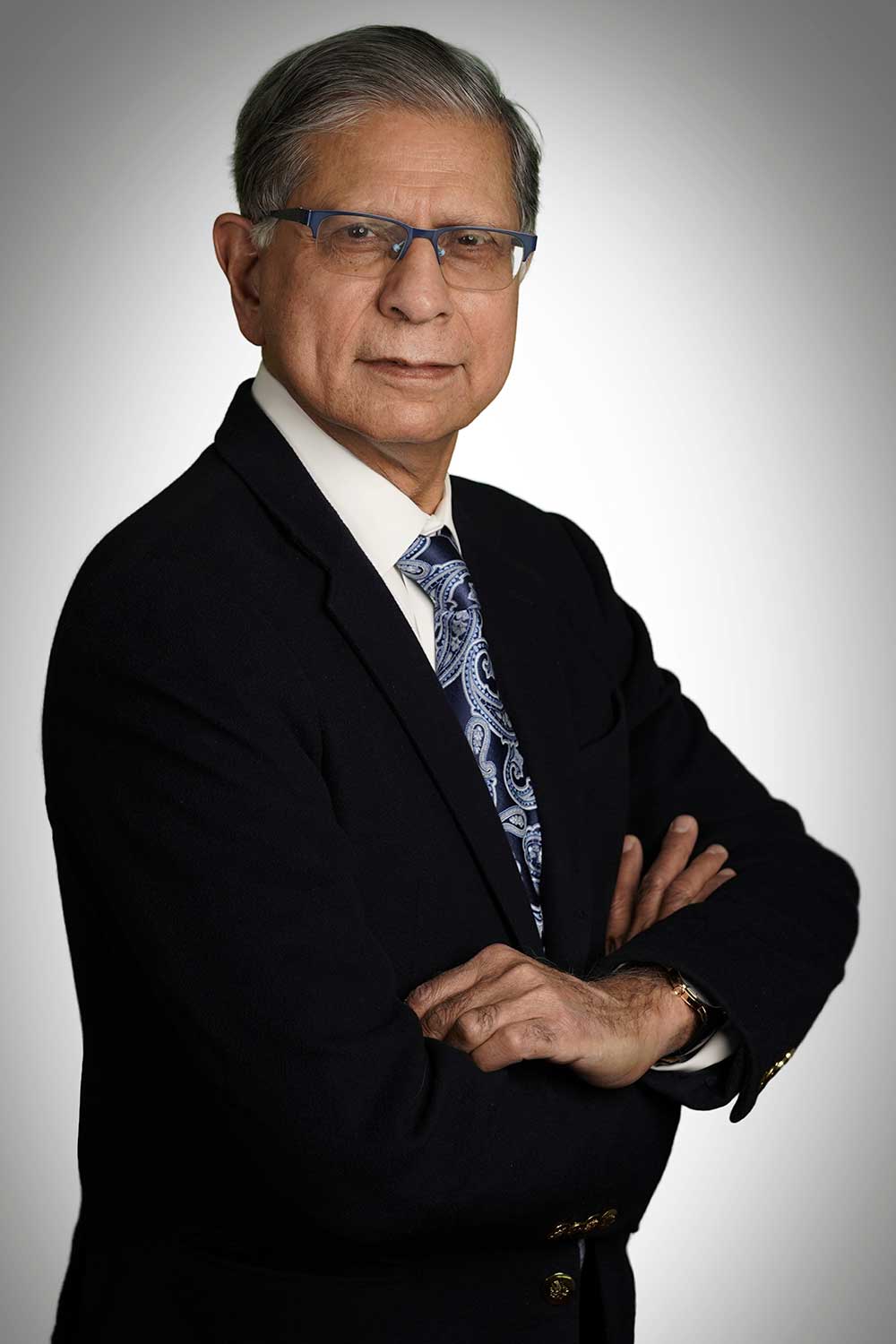 Headshot of retired neurosurgeon Dr. Shahid wearing a black suit angled left