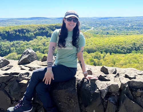 NH Spine Patient Carolina Herrera sitting on a rock wall with scenic landscape in the background