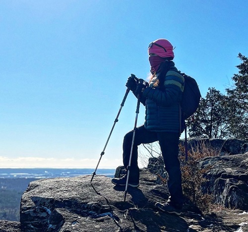 NH Spine Patient Carolina Herrera atop a mountain with hiking gear on 