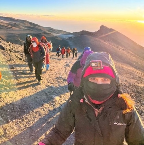 NH Spine Patient Carolina Herrera climbing Mt Kilimanjaro with the mountains and sunset in the background